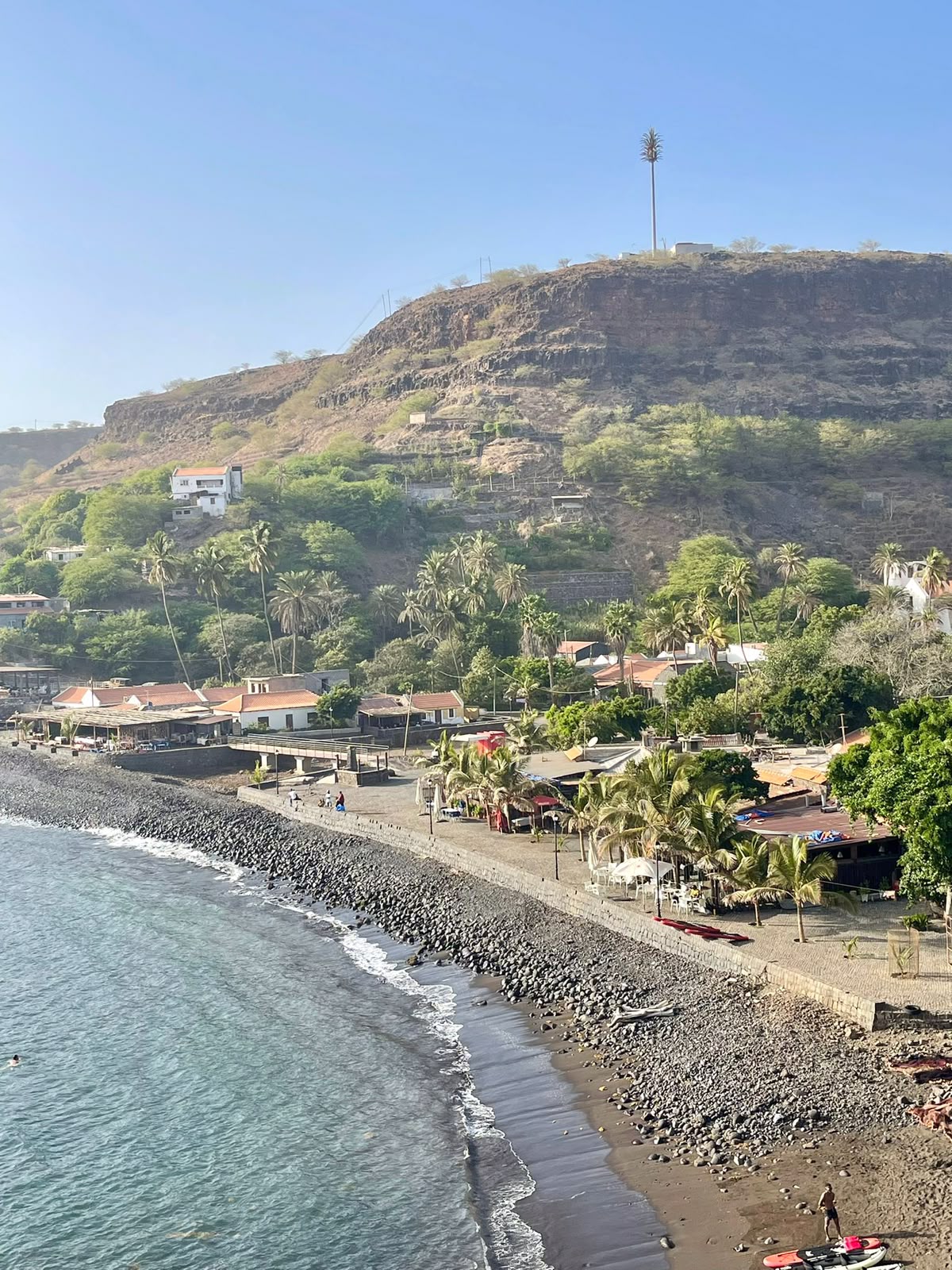 Pebble beach, palm trees and coastal village at Cidade Velha on Santiago island